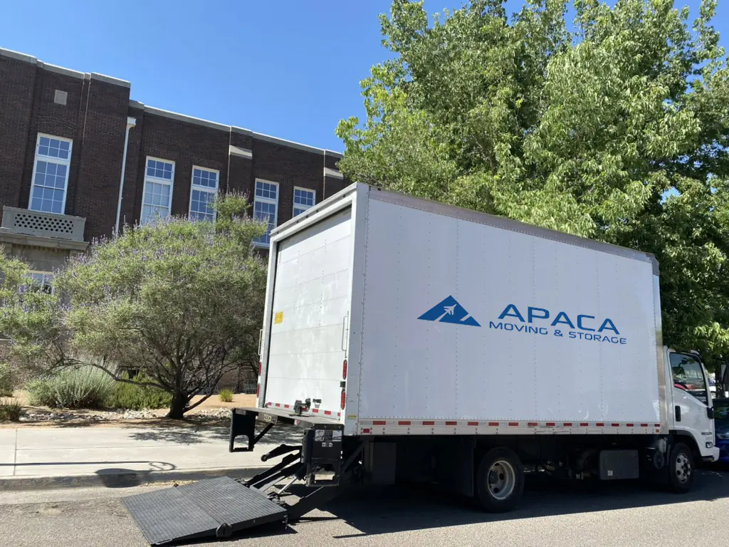 small APACA moving truck in front of a brick building