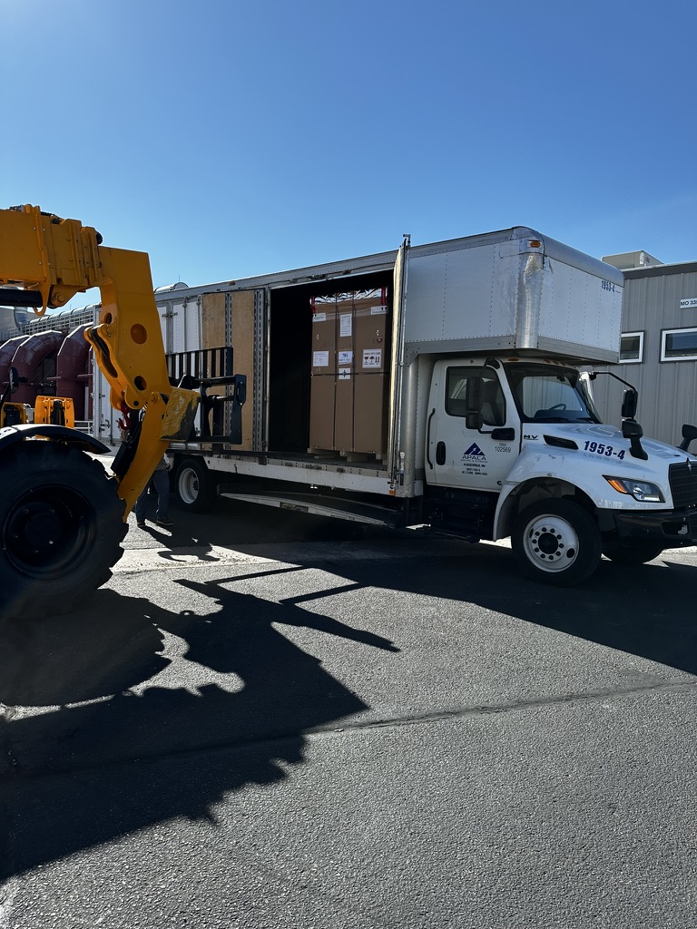 forklift removing a special delivery of an over-sized item from a moving truck.
